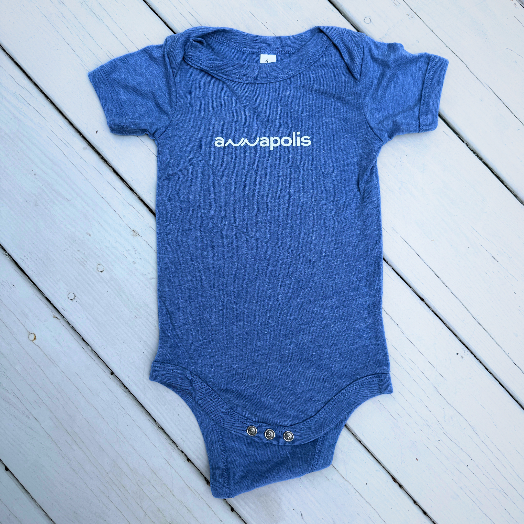 Coastal blue BELLA+CANVAS baby onesie with white lowercase annapolis wave logo