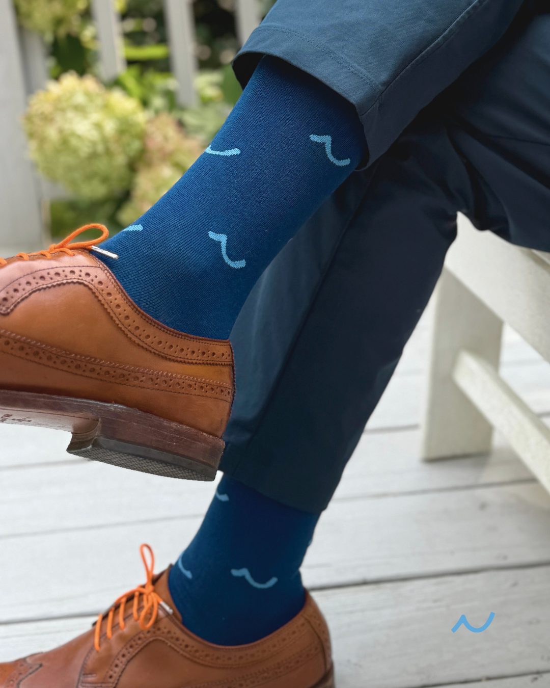 Person wearing blue socks with white patterns, standing on a wooden deck.